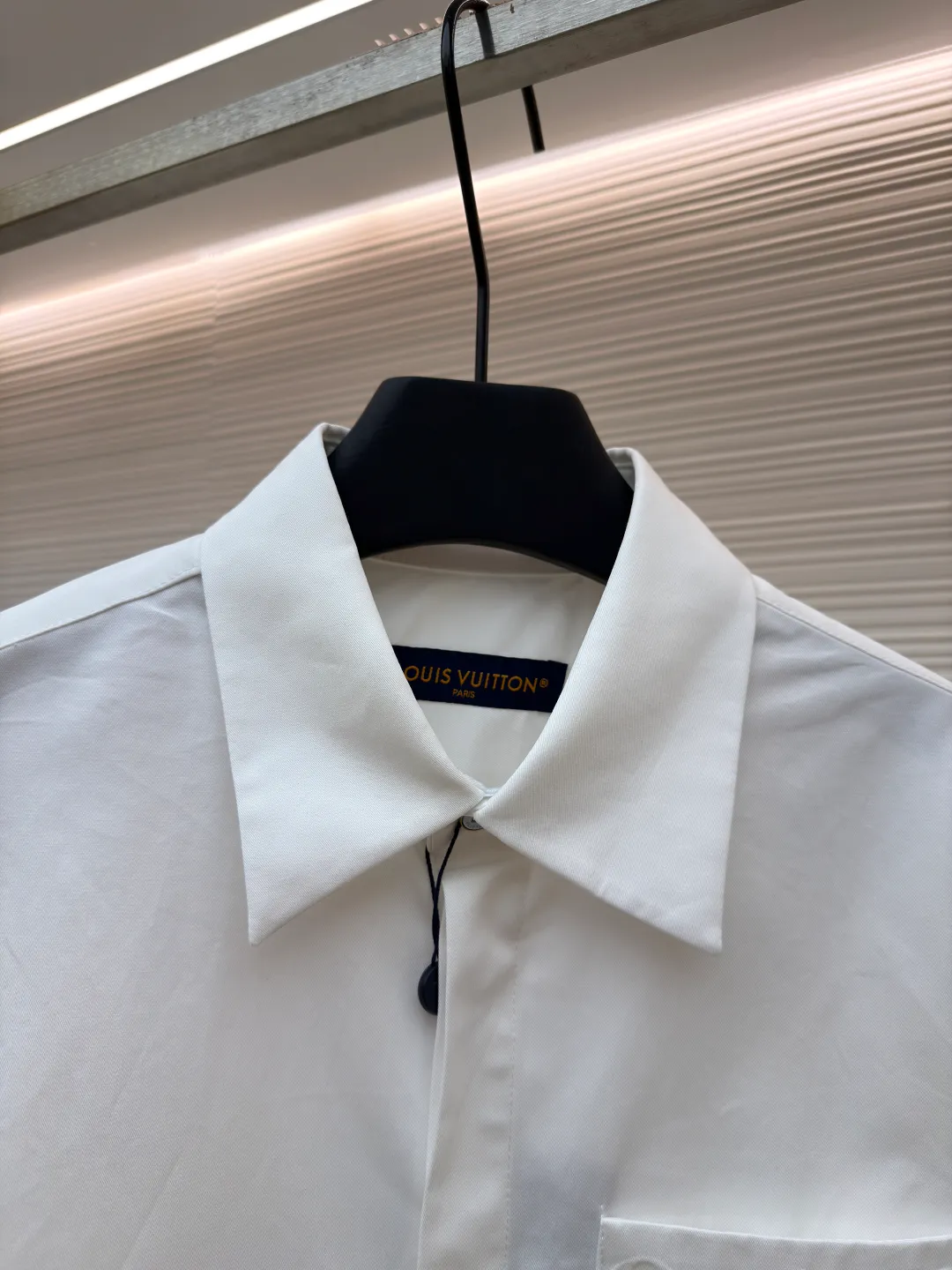 LOUIS VUITTON Embossed Pocket Lapel Shirt ●Original version: Purchased and developed for 3989 ●Item number: 1681491-B05 ●Fabric: Cotton twill woven fabric ●Technology: Concave embossed printing ●Color: white ●Version: Fitted version ●Weight: about 370 grams ●Size: XS-S-M-L ●Description: The twill pattern is obvious on the front of the fabric and blurry on the reverse. Single yarn is used in both warp and weft directions, and the linear density is close. The warp density of the fabric is slightly higher than the weft density, and the hand feel is relatively soft. The fabric has excellent stability, is not easy to deform, and prevents bulging; cotton fiber has good hygroscopicity, which keeps the fabric in a water balance, making people feel comfortable, and adding to the sophistication of the fabric. The concave and convex embossing process is formed by heating and shaping the upper and lower dies. The rollers press the fabric at a certain temperature, and the three-dimensional hierarchical convex surface is produced through mechanical embossing. The fabric produces a concave and convex pattern with a relief-style three-dimensional effect and a special gloss effect. The three-dimensional shape, pattern and text have a strong three-dimensional sense, adding a decorative art effect, clear layers, concentrated three-dimensional image, and accurate perspective angle. The collar can be adjusted with buttons for both formality and comfort; the pleats and tabs at the back are classic shirting techniques, with the pleats providing extra room for movement and the tabs keeping the shirt in shape when hanging. The button front uses custom-fit buttons that are positioned accordingly, and together these details ensure the shirt's functionality and crisp look. The overall wiring is straight and delicate, the fabric is comfortable and soft, and the color is consistent without color difference. It can be matched with the same style to create a fashionable look and control various occasions. Customized accessories, complete with three standards, same style for men and women!